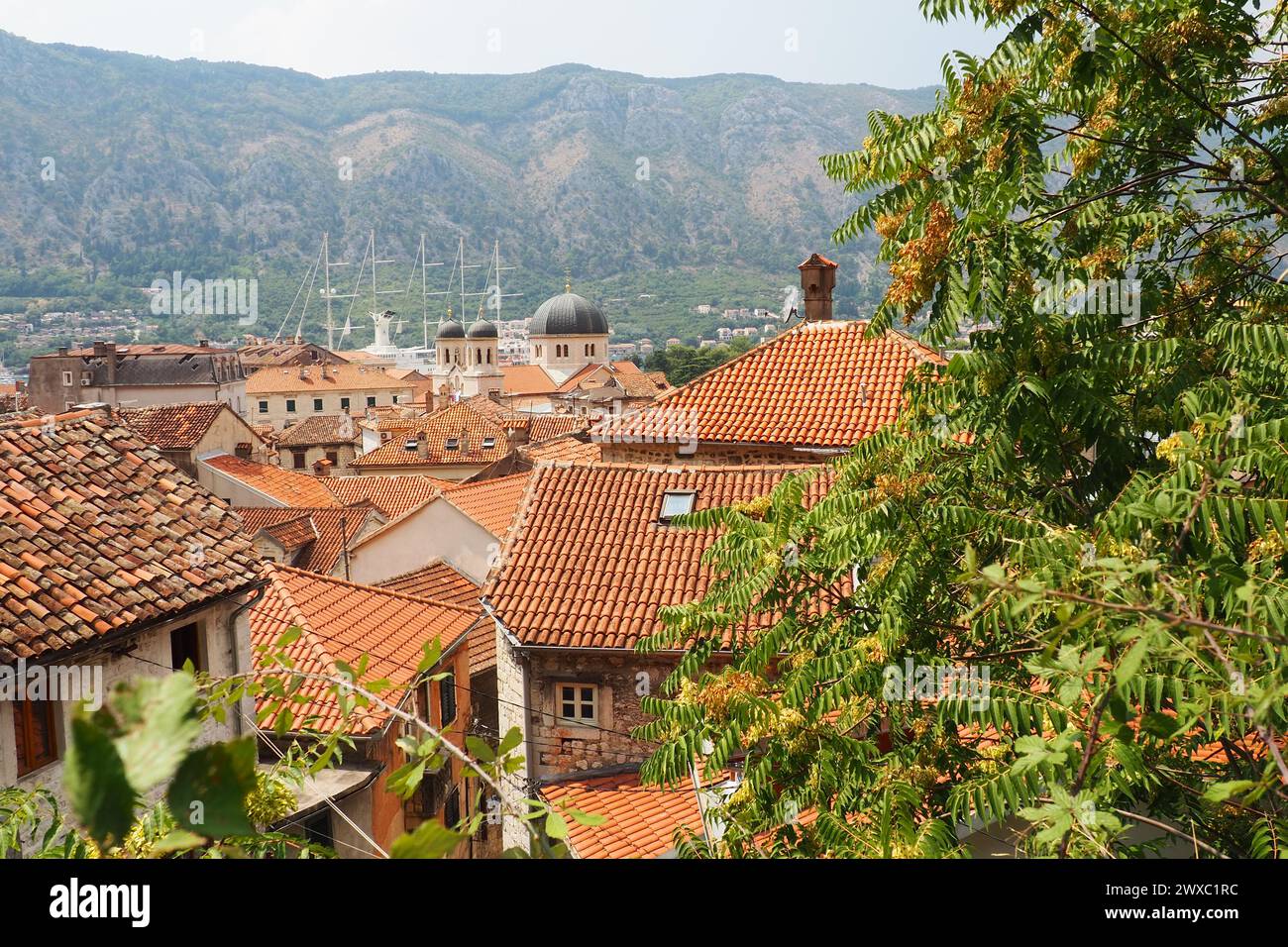 Kotor è una città costiera del Montenegro. Baia di Cattaro. Tetti di tegole rosse, montagne e camini di una nave turistica. Escursioni e turismo. Cattedrale di sa Foto Stock