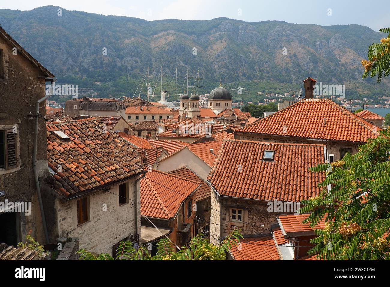 Kotor è una città costiera del Montenegro. Baia di Cattaro. Tetti di tegole rosse, montagne e camini di una nave turistica. Escursioni e turismo. Cattedrale di sa Foto Stock