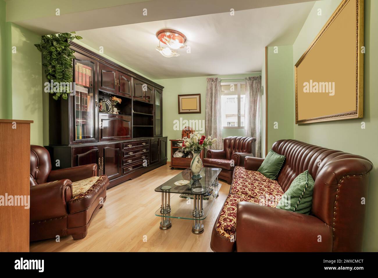 soggiorno di una casa arredata con mobili antichi e un divano rivestito in marrone scuro Foto Stock