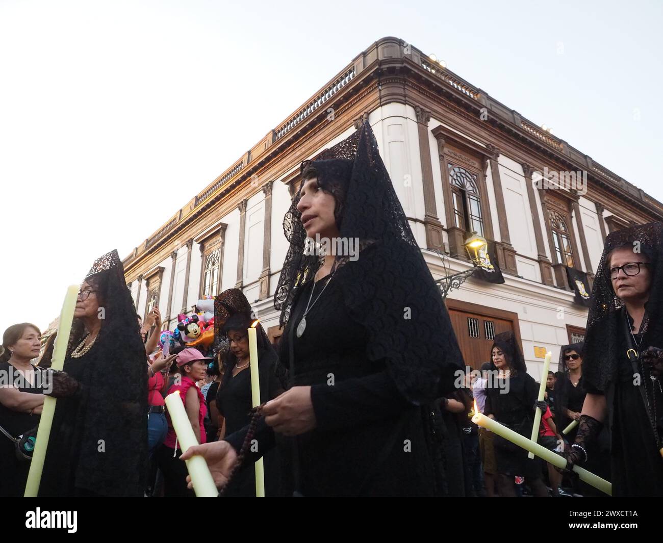 Lima, Perù. 29 marzo 2024. Devoti donne vestite di nero che indossano mantilla e pettine, trasportano candele in processione religiosa il venerdì Santo, nell'ambito delle celebrazioni della settimana Santa 2024 a Lima crediti: Fotoholica Press Agency/Alamy Live News Foto Stock