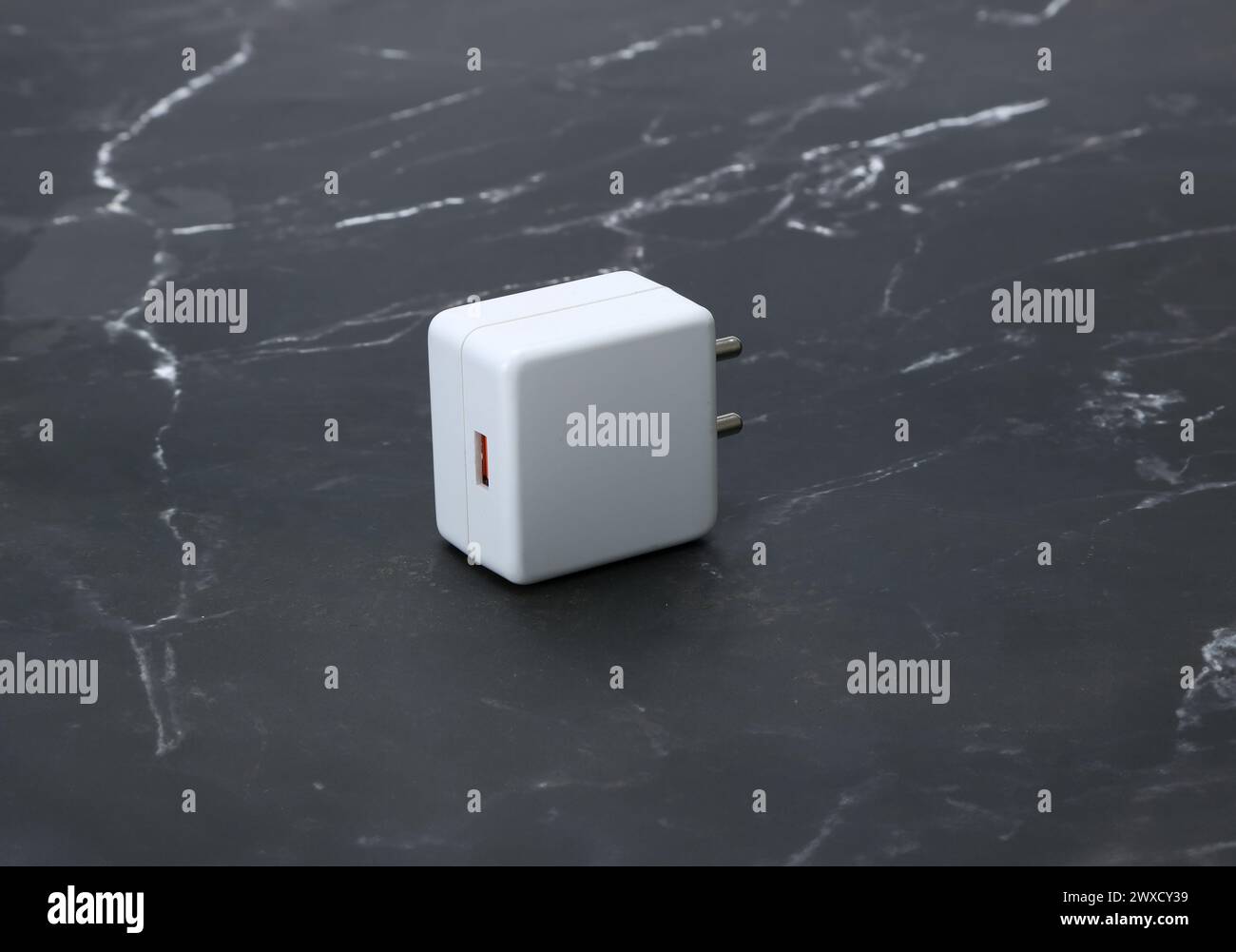 caricabatterie a due pin bianco con isolamento su sfondo in marmo nero Foto Stock