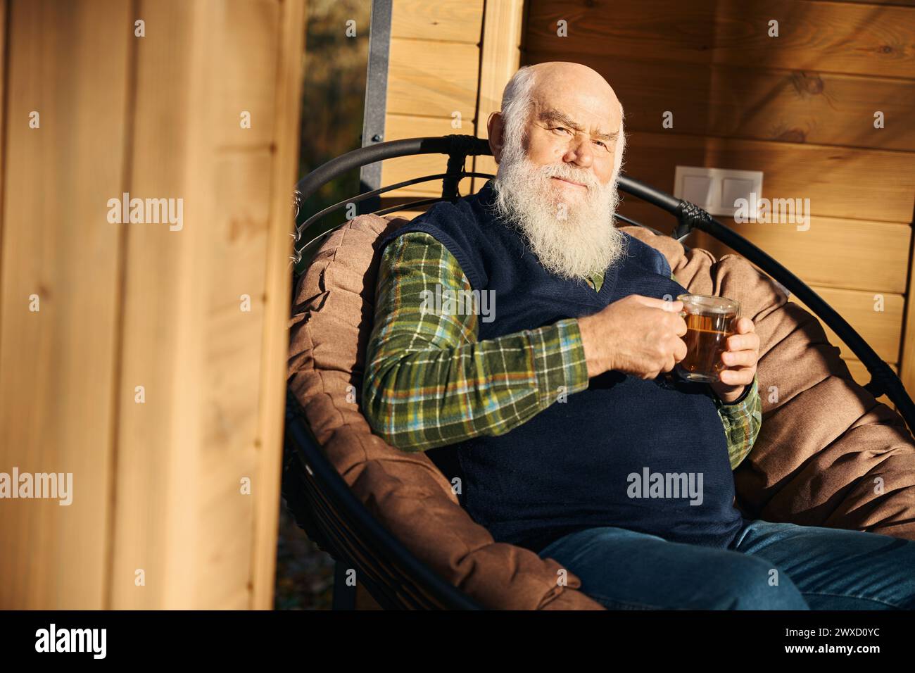 Il vecchio dai capelli grigi è seduto sulla veranda con una tazza di tè Foto Stock