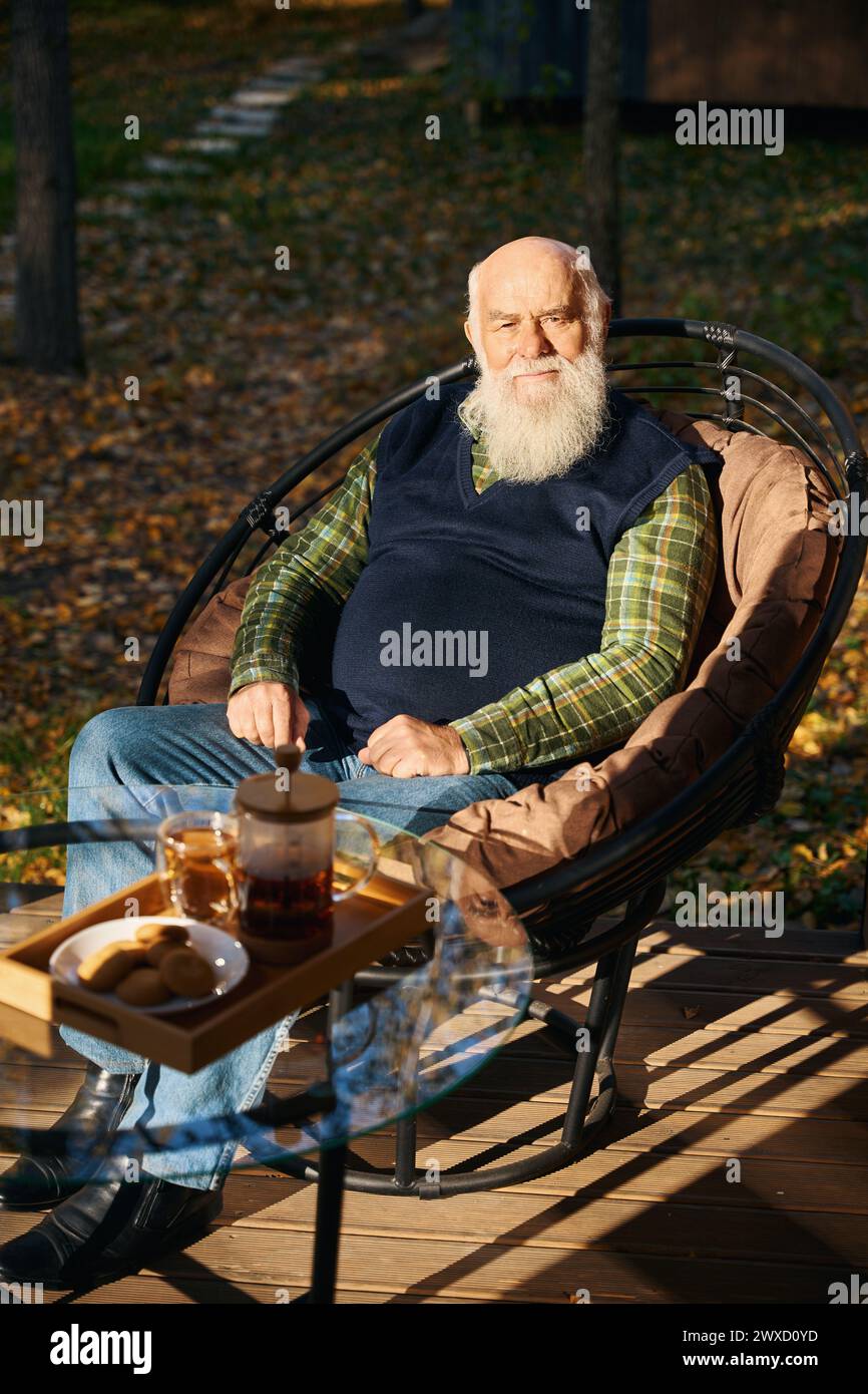 Il vecchio dai capelli grigi sta prendendo il tè sulla veranda Foto Stock