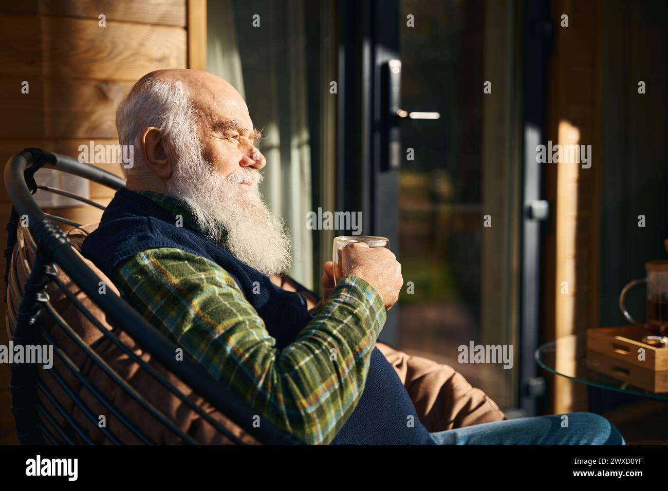 L'uomo anziano è seduto sulla veranda con una tazza di tè Foto Stock