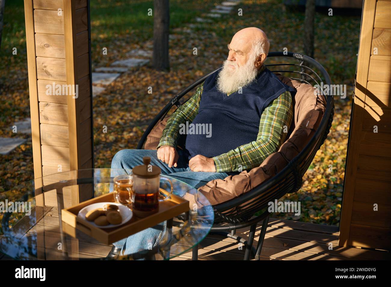 Il vecchio barbuto sta bevendo il tè sulla veranda Foto Stock