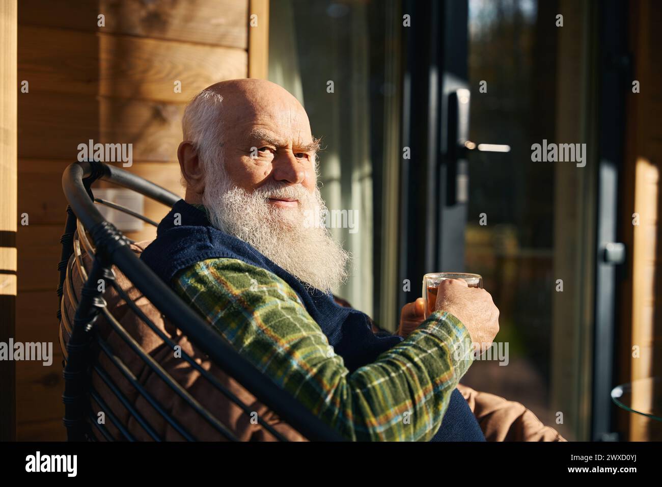 L'anziano uomo dai capelli grigi è seduto sulla veranda con una tazza di tè Foto Stock