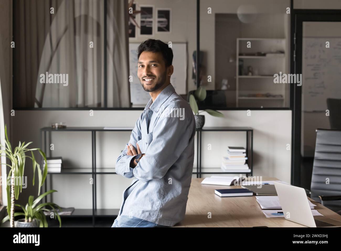 Felice fiducioso bello giovane uomo d'affari indiano in posa in ufficio Foto Stock