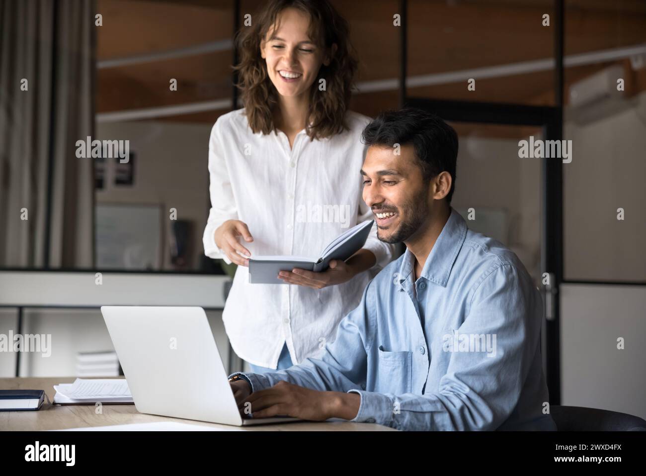 Allegri colleghi di lavoro diversi che parlano e ridono del notebook Foto Stock