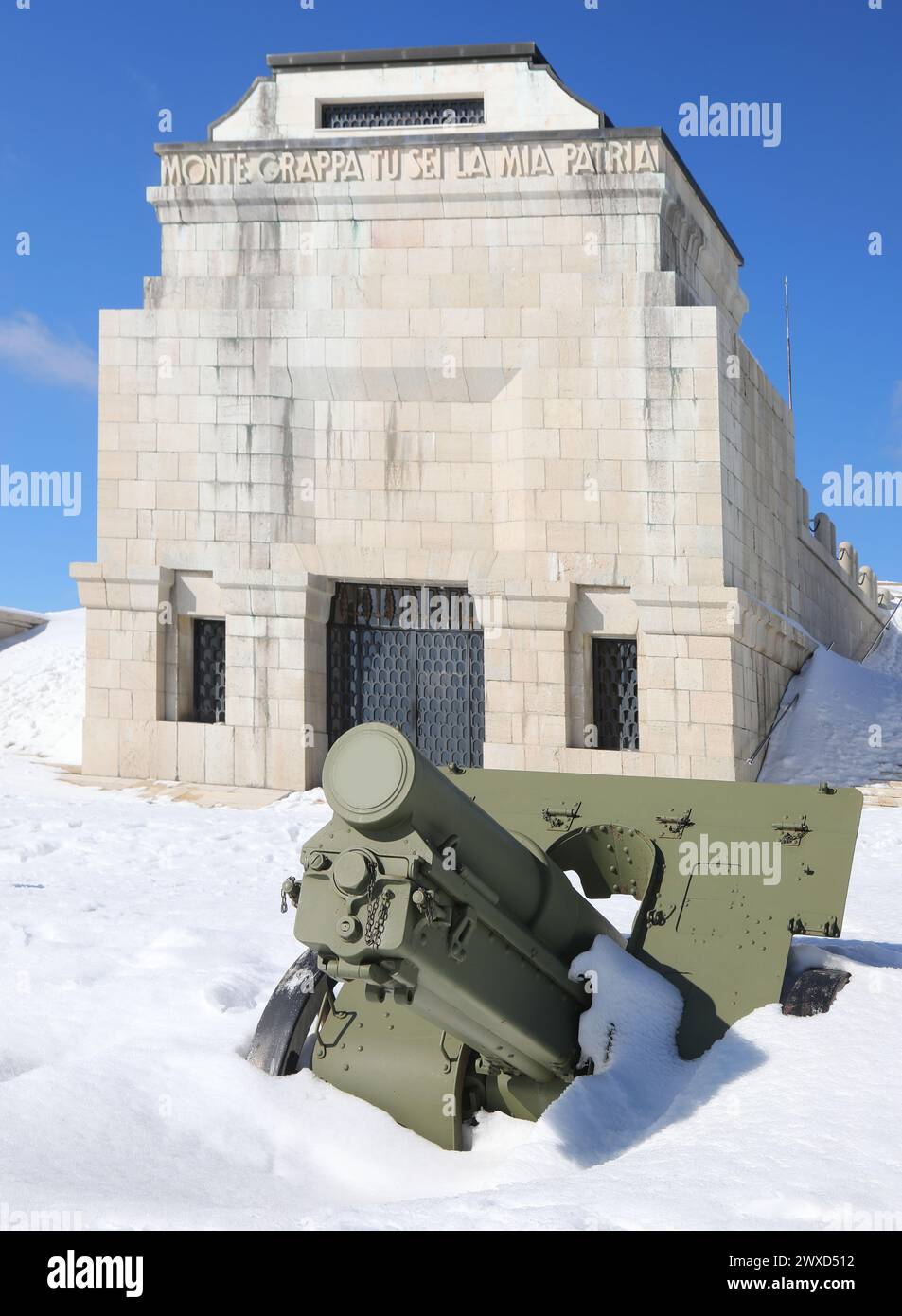 Pieve, TV, Italia - 13 marzo 2024: Memoriale militare con cannone sulla neve e testo che significa Grappa Monte tu sei la mia patria Foto Stock