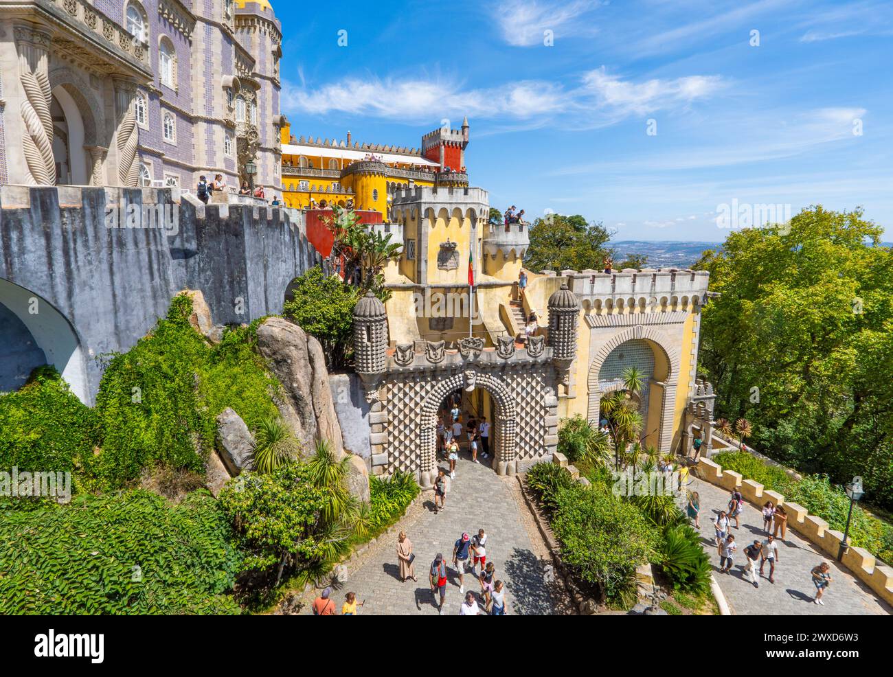 Vista panoramica aerea dei turisti che visitano e scattano foto al Palácio da pena lungo l'ingresso e il sentiero collinare sotto un cielo azzurro soleggiato. Sintra, Foto Stock