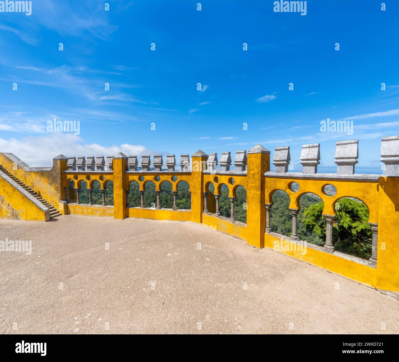 Ampia vista del cortile ad arco con archi in stile moresco del Palácio da pena, affacciato sul cielo azzurro cristallino e sulla catena montuosa di Sintra. Portogallo. Foto Stock