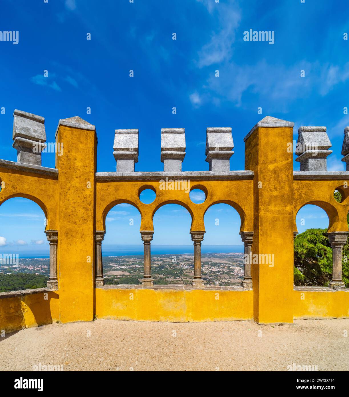 Archi moreschi del cortile ad arco con le pareti dipinte di giallo del Palácio da pena, uno dei castelli più belli d'Europa, sotto un chiaro edificio Foto Stock