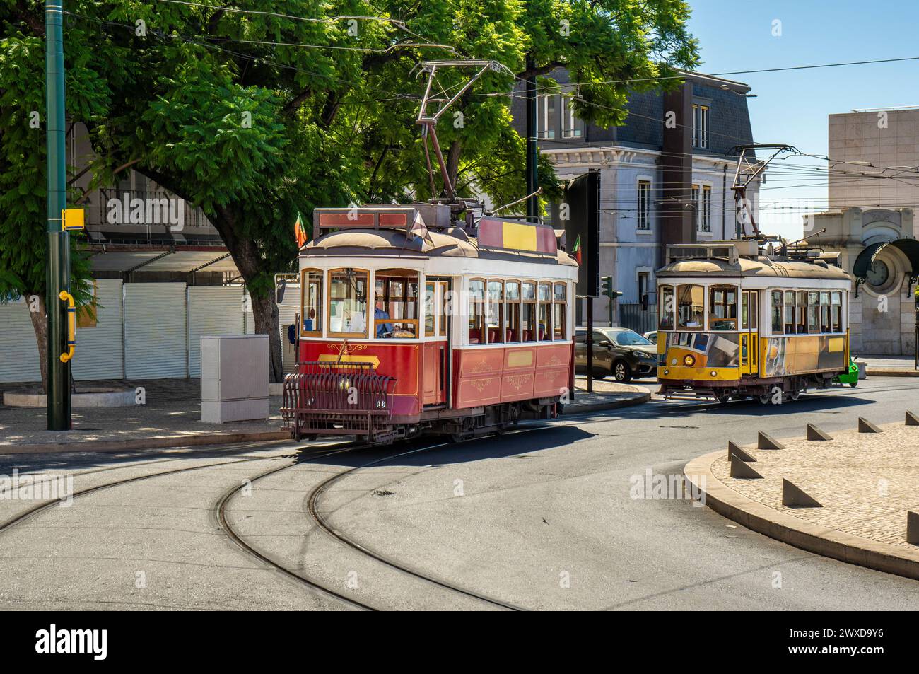 Famoso e tipico vecchio tram rosso e giallo, splendidamente decorato che conserva i disegni originali, circolando sui binari di una tipica strada di Lisbona Foto Stock