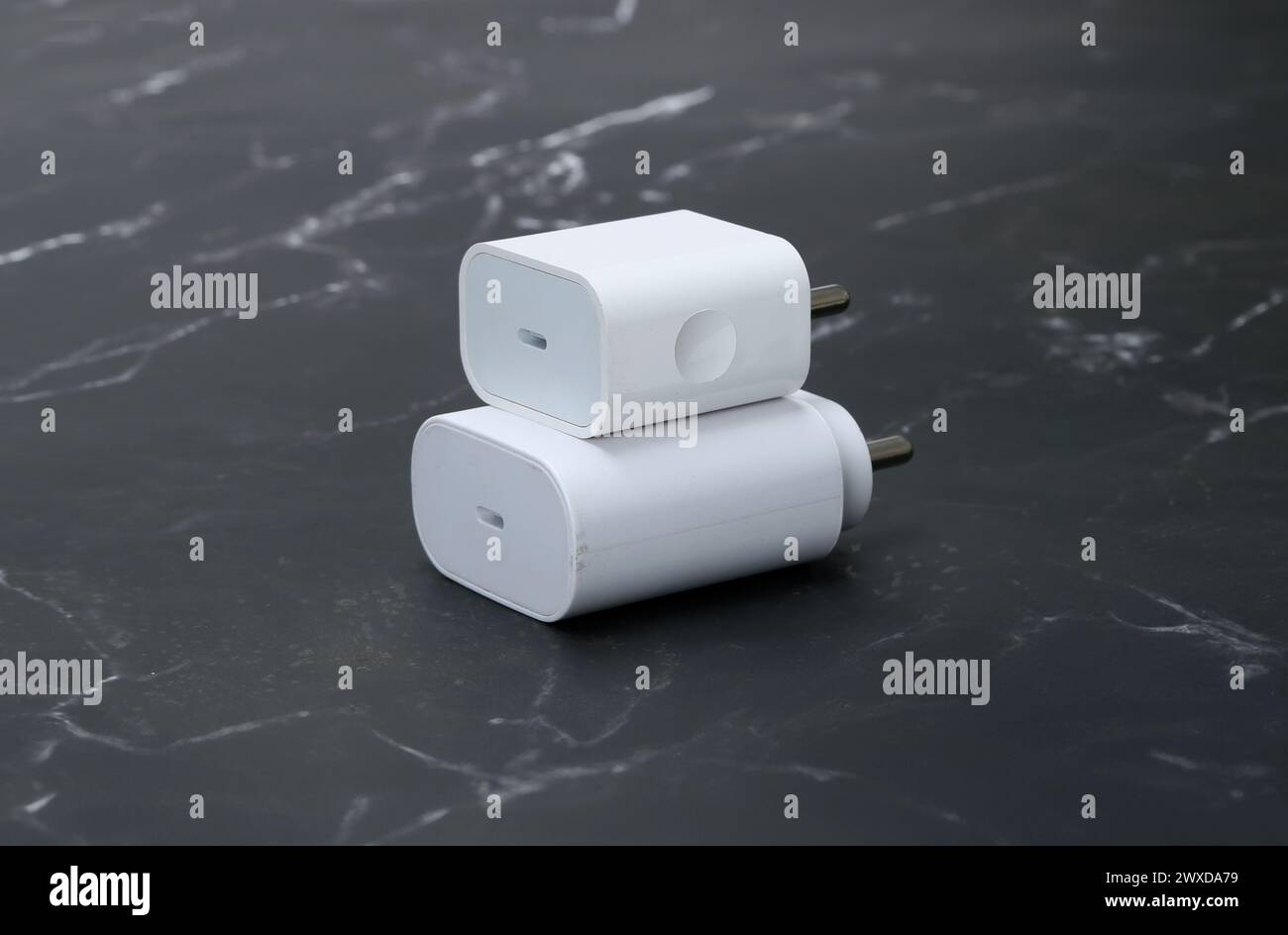 caricabatterie per smartphone bianchi su sfondo in marmo nero Foto Stock