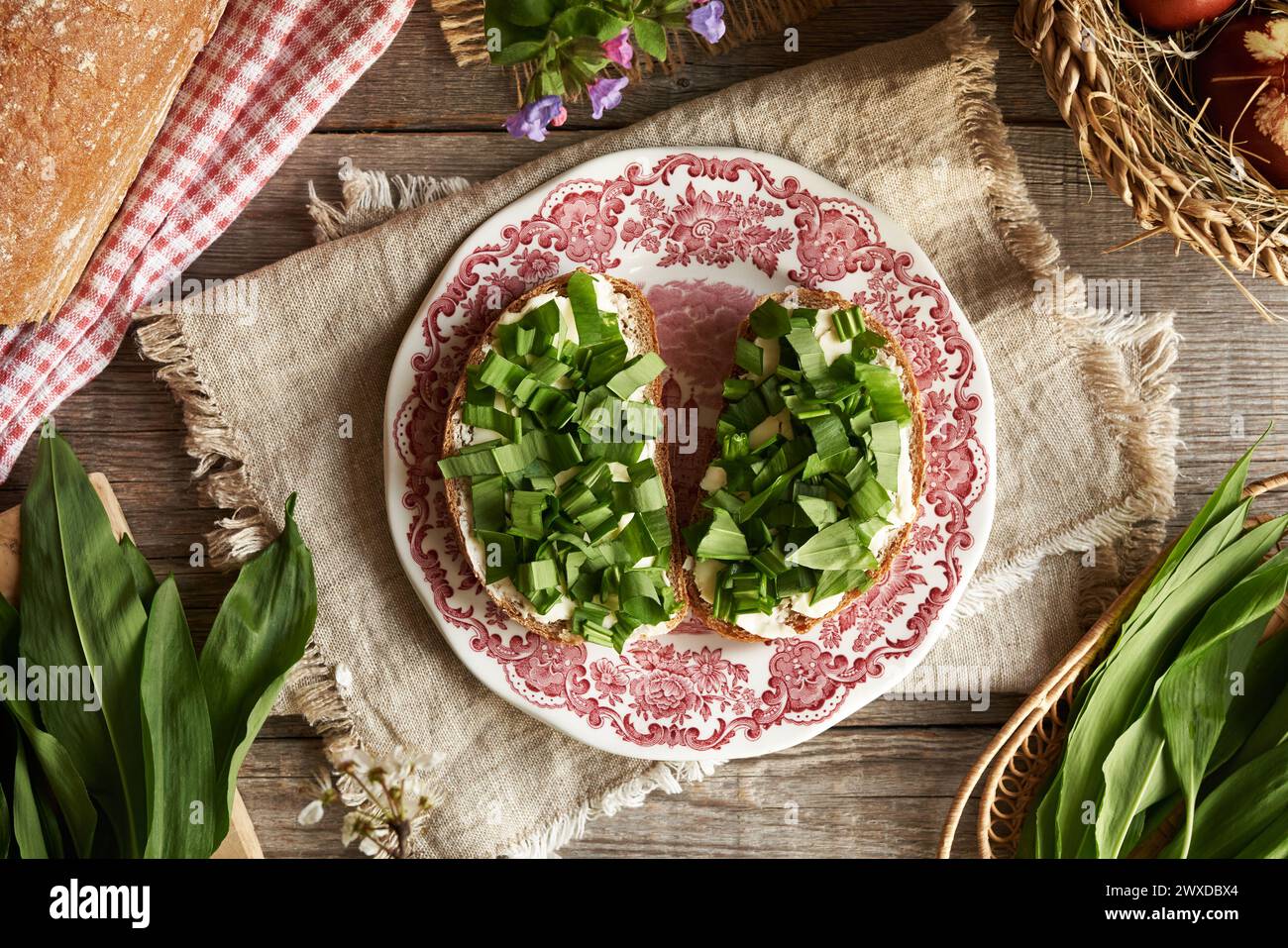 Tagliate fresche di aglio selvatico o foglie di ramson su due fette di pane a pasta madre con burro Foto Stock