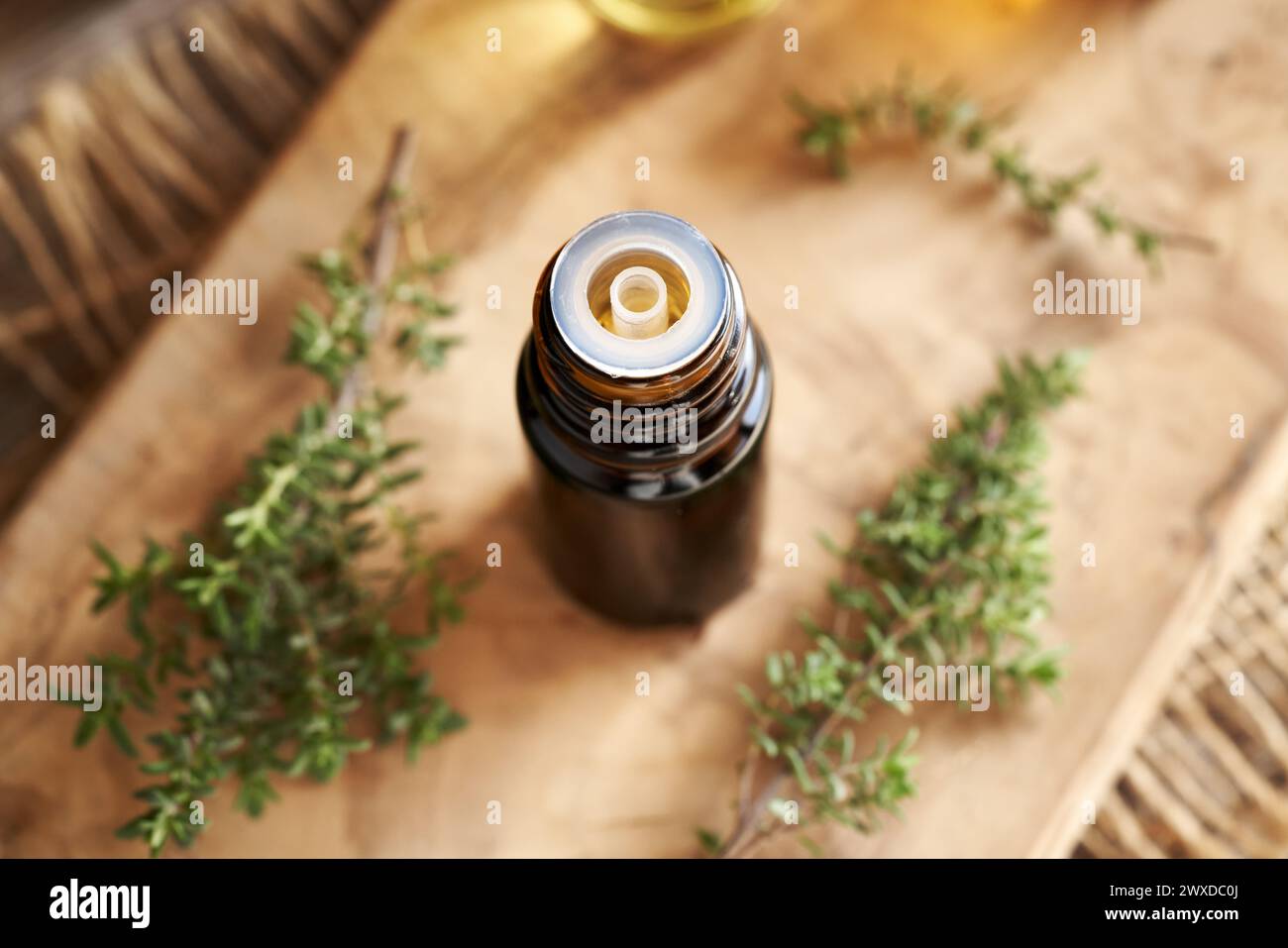 Una bottiglia scura di olio essenziale aromaterapico con timo fresco su un tavolo di legno Foto Stock
