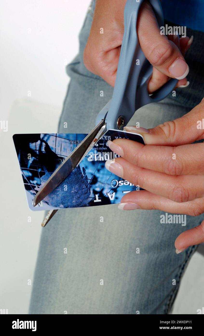 La ragazza taglia le carte di credito con le forbici Foto Stock