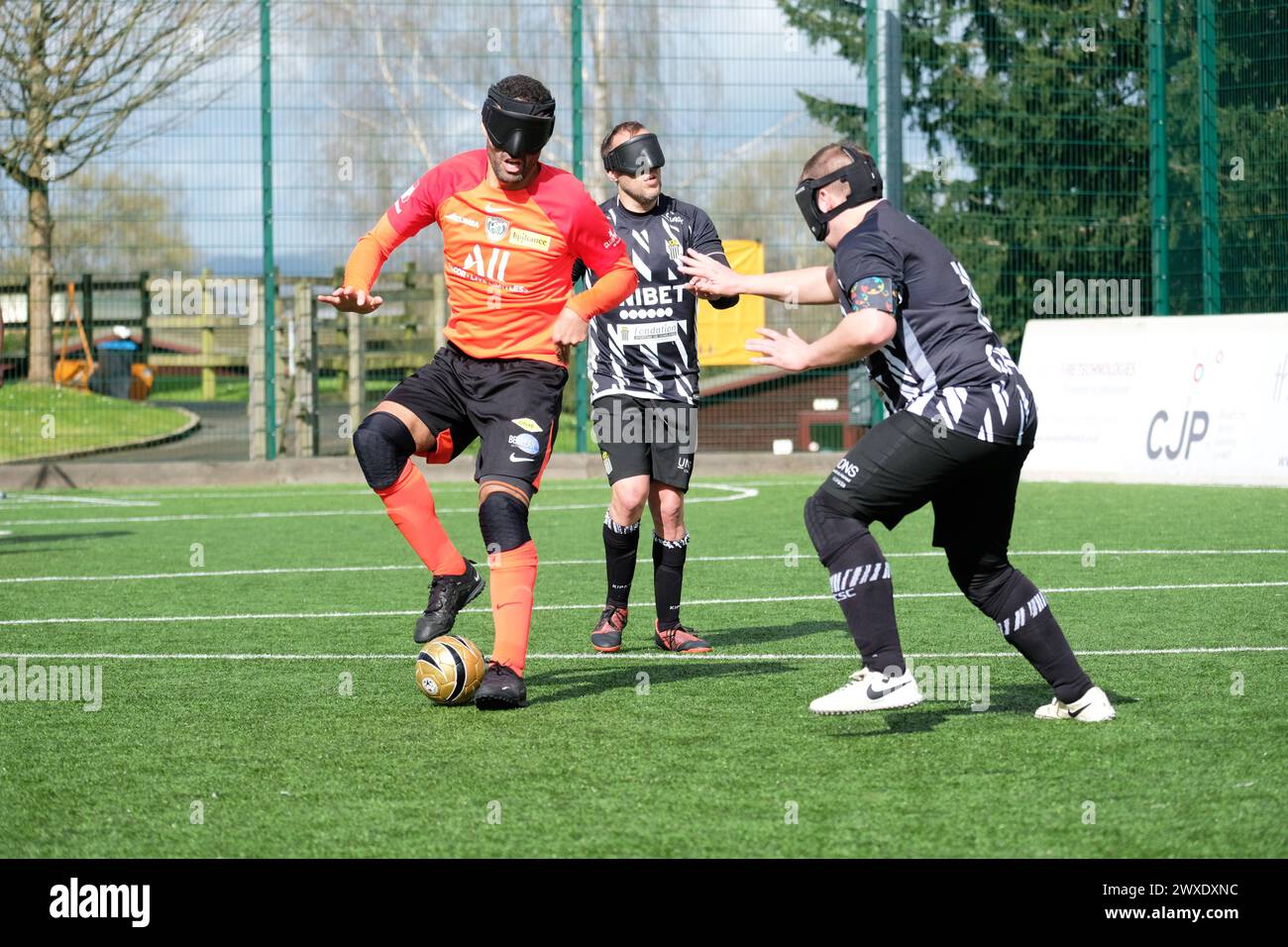 Royal National College for the Blind, Hereford, Regno Unito – sabato 30 marzo 2024 – terza fase della European Blind Football League ( EBFL ) tenutasi presso il Royal National College for the Blind di Hereford, con sei squadre europee. La sfera è dotata di cuscinetti a sfere che battono per aiutare i giocatori a localizzarla. Un giocatore del club francese Bondy Cecifoot Club ( maglia arancione ) è sfidato da un giocatore del club belga Cecifoot Charleroi. Foto Steven May / Alamy Live News Foto Stock