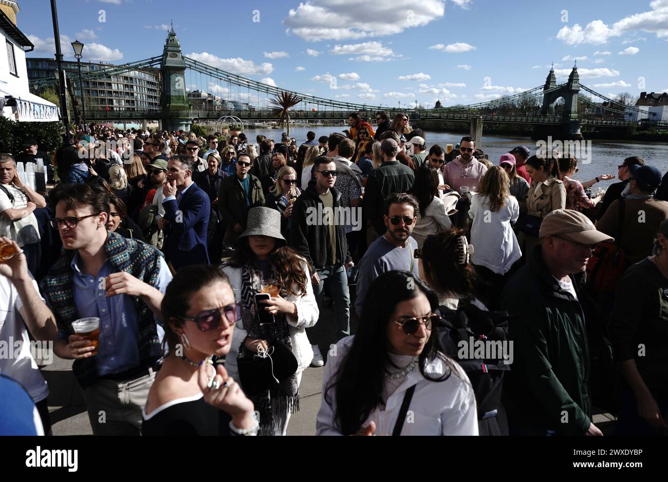 Gli spettatori vicino all'Hammersmith Bridge aspettavano l'inizio della gara prima della Gemini Boat Race 2024 sul Tamigi, a Londra. Data foto: Sabato 30 marzo 2024. Foto Stock