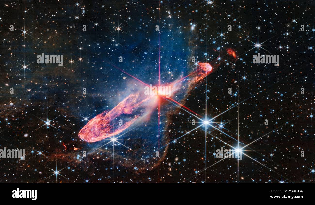 Il James Webb Space Telescope della NASA cattura una coppia di stelle che formano attivamente, note come Herbig-Haro 46/47, in una luce vicino all'infrarosso ad alta risoluzione. Visto al centro dei picchi di diffrazione rossi, appare come un macello bianco-arancione. Herbig-Haro 46/47 è un oggetto importante da studiare perché è relativamente giovane - solo poche migliaia di anni. I sistemi stellari impiegano milioni di anni per formarsi pienamente. Obiettivi come questo danno ai ricercatori un'idea di quante stelle di massa si raccolgono nel tempo, permettendo loro di modellare come il nostro Sole, che è una stella a bassa massa. CREDITI: NASA, ESA, CSA Foto Stock