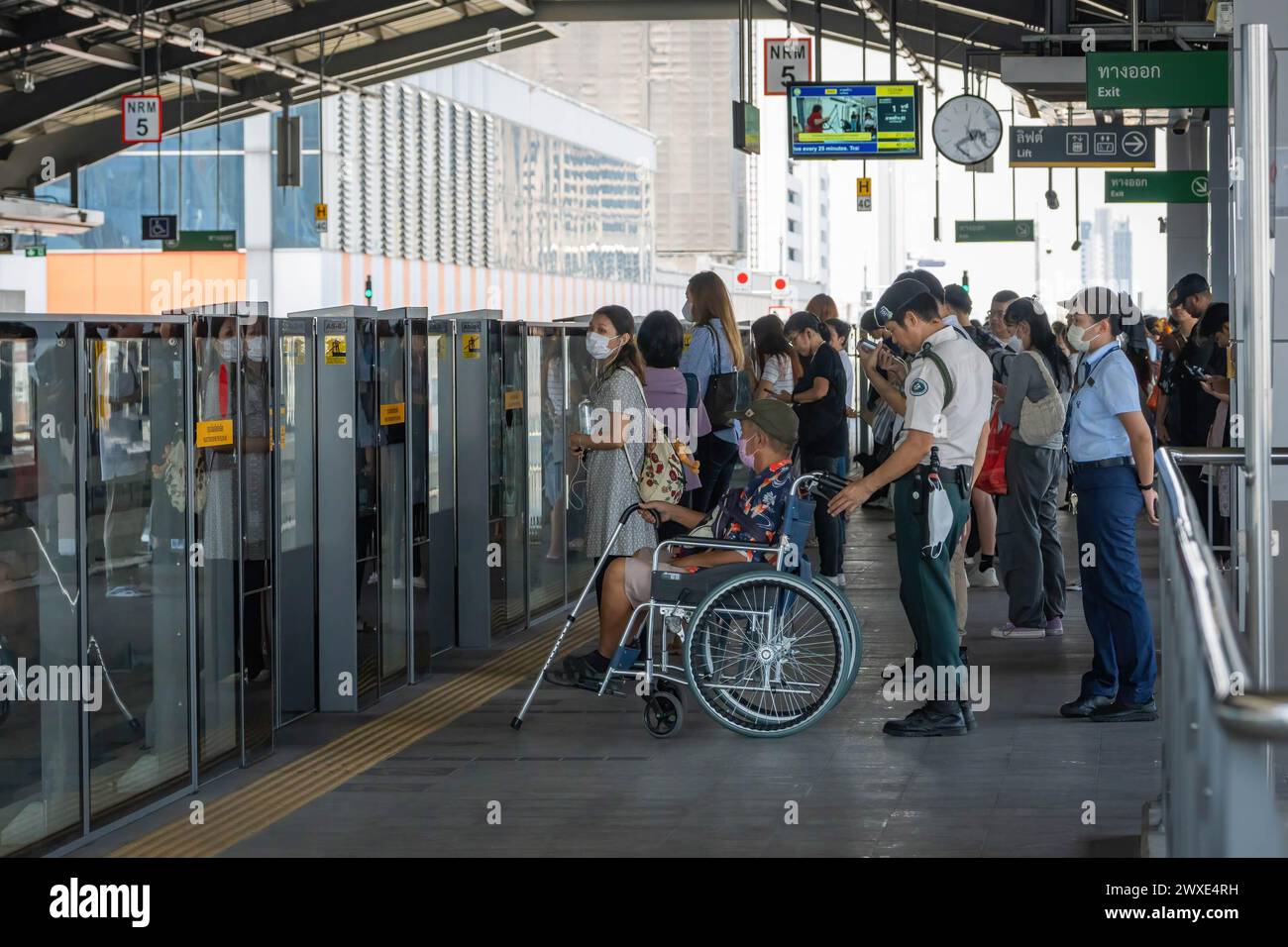 I passeggeri e un anziano su una sedia a rotelle aiutati dal personale della metropolitana sono visti in attesa della monorotaia della linea gialla, sul binario della stazione Lat Phrao, a Bangkok. La monorotaia prodotta dalla multinazionale francese Alstom, di proprietà della Metropolitan Rapid Transit Authority (MRTA) in Thailandia, ha ripreso i servizi della linea gialla dopo che alcune parti sono cadute dall'IT, danneggiando i veicoli ma non causando lesioni. L'incidente è avvenuto due mesi fa, quando una ruota di gomma di un treno della linea gialla è caduta e ha colpito un taxi sulla strada sottostante. (Foto di Nathalie Jamois/SOPA Images/Sipa USA) Foto Stock