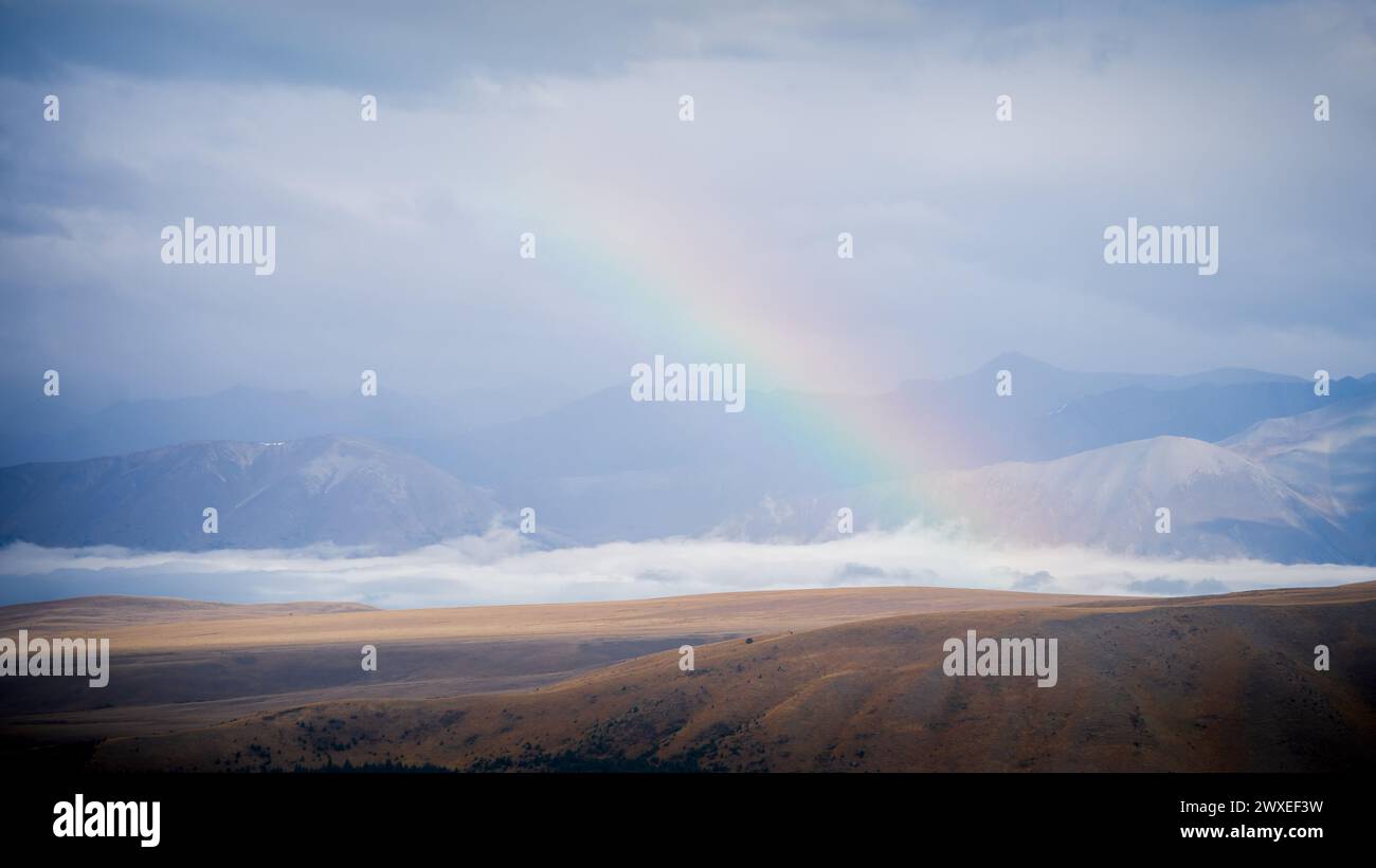 Arcobaleno che si innalza sul paesaggio alpino subito dopo la tempesta, in nuova Zelanda. Foto Stock