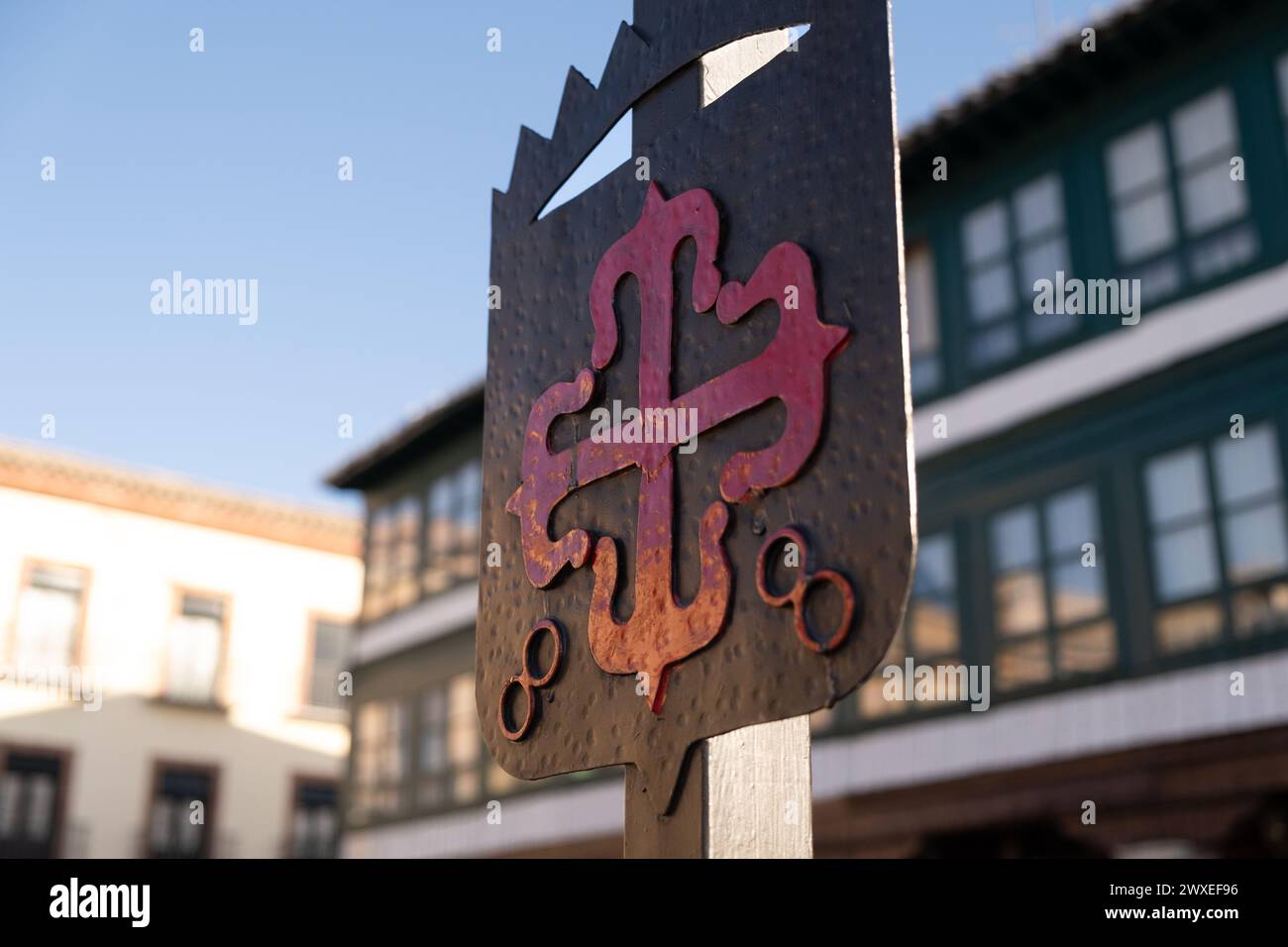 Dettaglio dell'emblema dell'ordine di Calatrava iluminato dal sole del mattino. Croce greca rossa con Fleur-de-lis alle sue estremità, in Plaza Mayor di Almagro Foto Stock