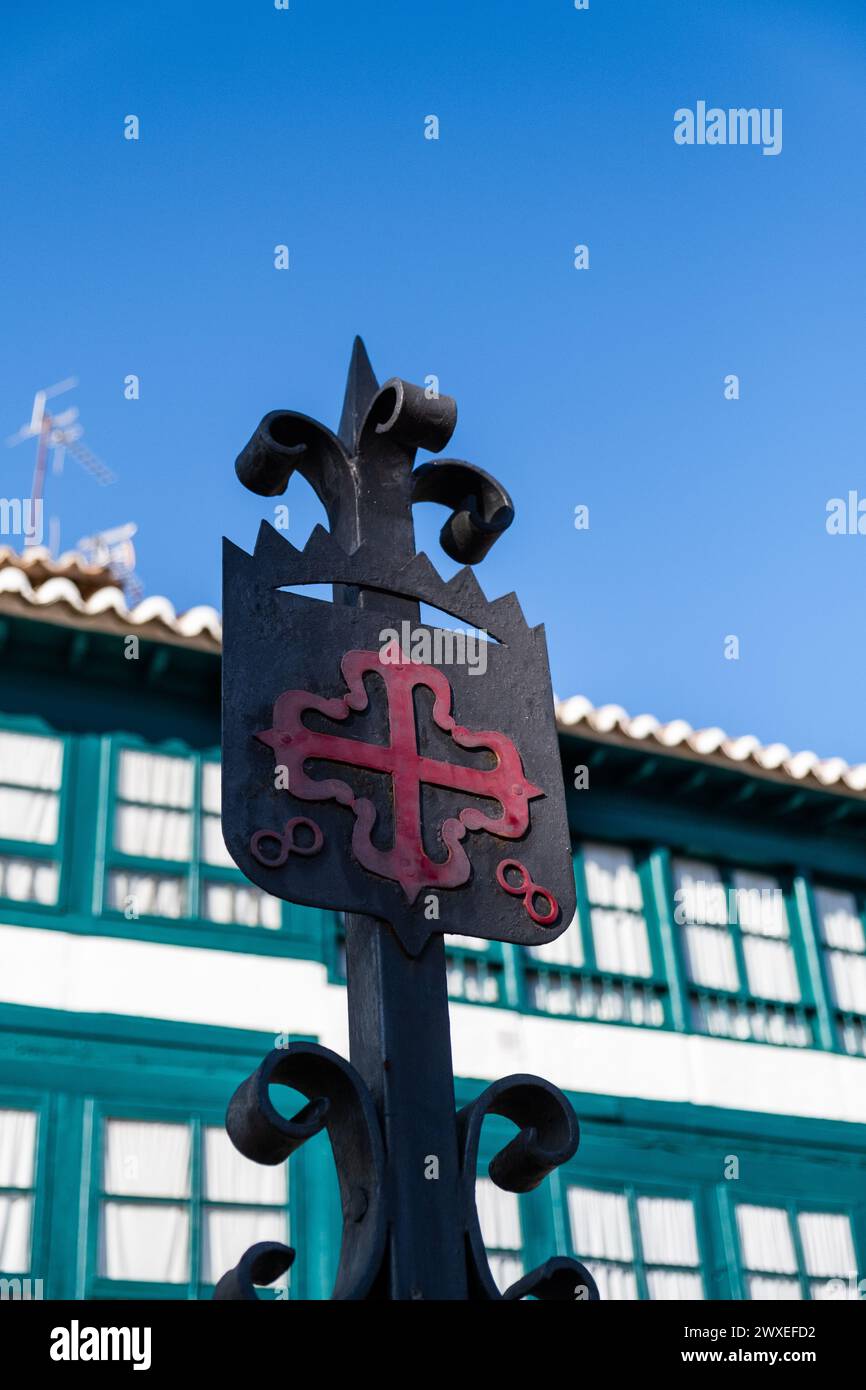 Emblema classico dell'ordine di Calatrava, croce greca rossa con fleur-de-lis alle sue estremità, in Plaza Mayor di Almagro, Ciudad Real con il tipico b Foto Stock