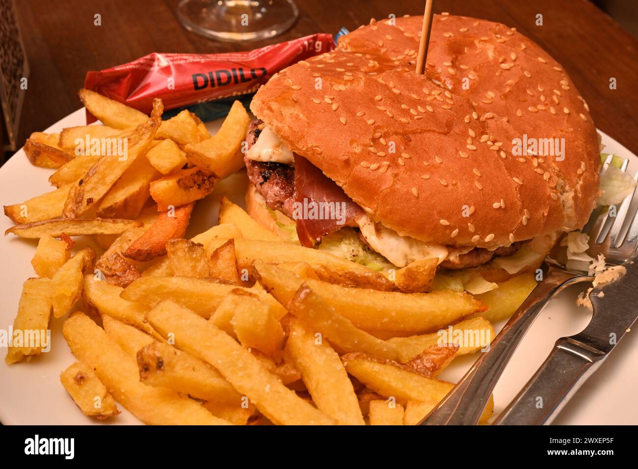 Hamburger con prosciutto e formaggio con patatine in panino con semi di sesamo Foto Stock
