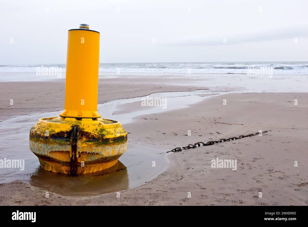 Un avvertimento giallo o una boa di navigazione si è strappata dai suoi ormeggi in mare durante una tempesta intensa e si è lavata su una spiaggia sabbiosa a pochi chilometri di distanza. Foto Stock