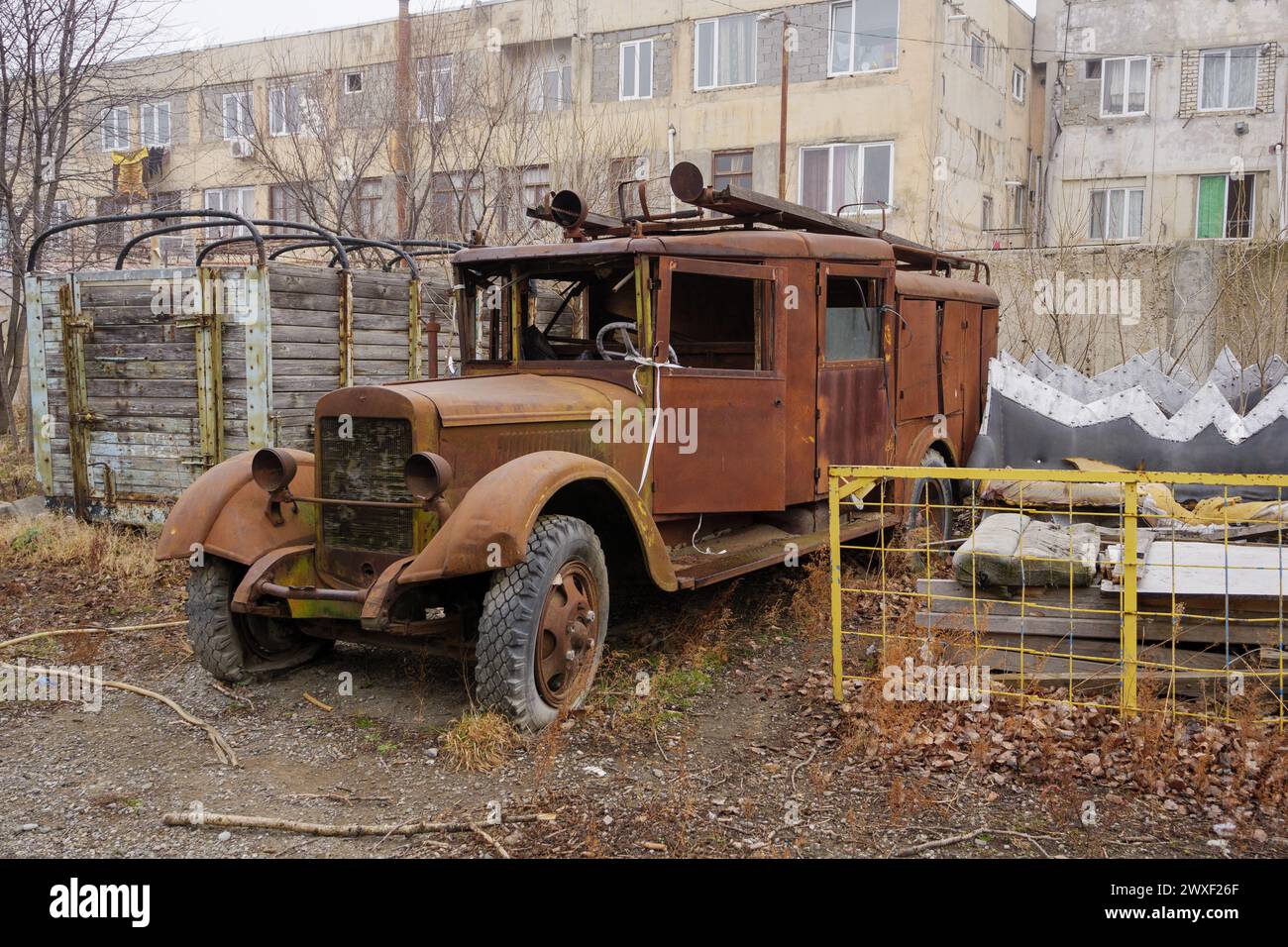 Un camion sovietico d'epoca arrugginito è abbandonato da edifici industriali. Foto Stock