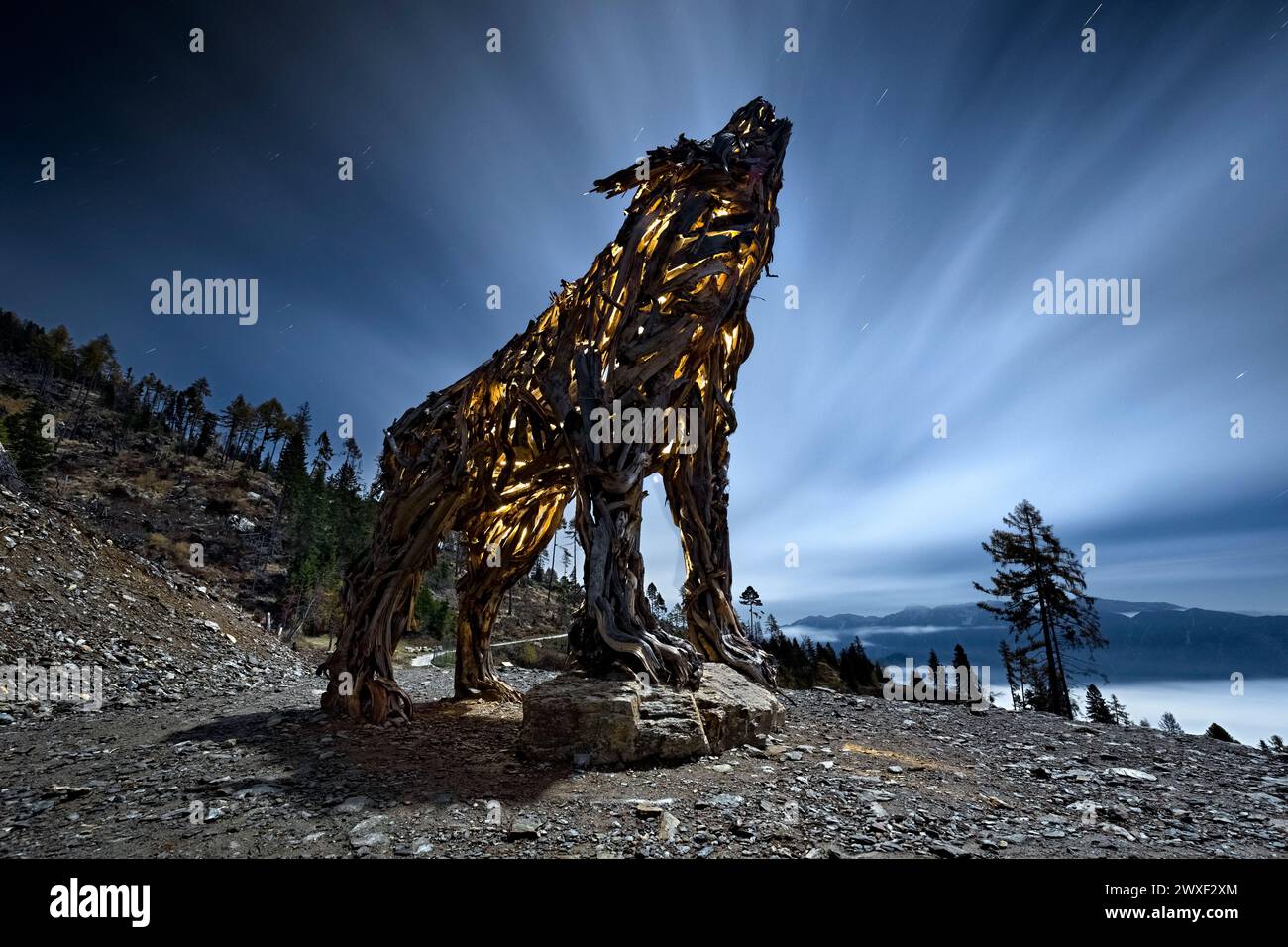 La "Lupa del Lagorai" in una notte di luna piena: Un'opera di arte della terra fatta di legno. Vetriolo, Levico Terme, Trentino, Italia. Foto Stock