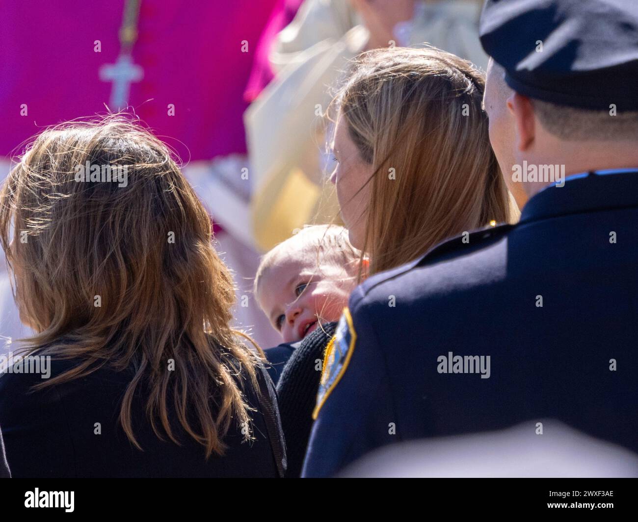New York, Stati Uniti. 30 marzo 2024. Una vedova tiene suo figlio in attesa che la bara venga scaricata. Il funerale per l'agente caduto della polizia di New York Jonathan Diller si è tenuto con centinaia di agenti di polizia allineati davanti alla St Rosa di Lima Chiesa cattolica Toman. Secondo i rapporti della polizia, l'agente Diller, di 31 anni, e il suo partner stavano facendo una fermata per un'auto parcheggiata illegalmente a far Rockaway. Durante l'incontro, un individuo nel veicolo brandiva un'arma da fuoco e la puntava agli ufficiali, provocando uno scambio di colpi di arma da fuoco. Credito: SOPA Images Limited/Alamy Live News Foto Stock