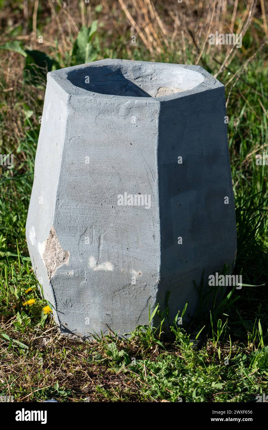 Sfumature sinfoniche. Esplorando la simmetria di luci e ombre attraverso il cestino pubblico in cemento nel parco. Foto Stock