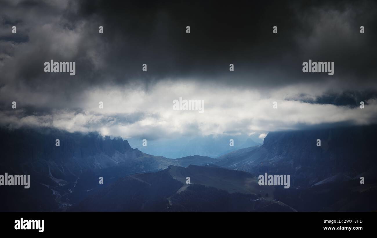 Meteo imprevedibilmente mutevole nelle Dolomiti, Italia, con nuvole di tempesta scure che incombono sulle montagne alpine e sulle valli stratificate Foto Stock