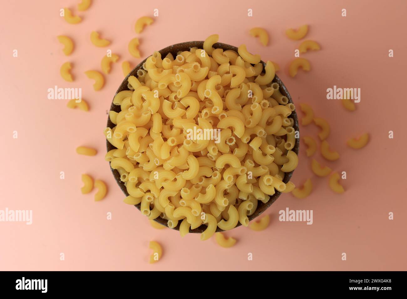 Vista dall'alto: Maccheroni a gomito essiccati crudi per cucinare la pasta, su una ciotola in ceramica Foto Stock