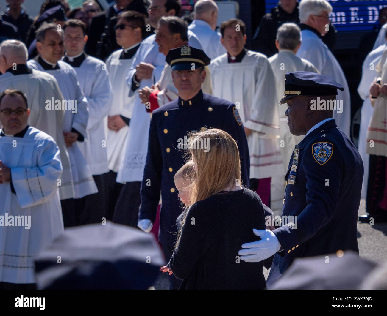 New York, Stati Uniti. 30 marzo 2024. La polizia di New York porta la vedova e il figlio verso il cuore e il clero. Il funerale per l'agente caduto della polizia di New York Jonathan Diller si è tenuto con centinaia di agenti di polizia allineati davanti alla St Rosa di Lima Chiesa cattolica Toman. Secondo i rapporti della polizia, l'agente Diller, di 31 anni, e il suo partner stavano facendo una fermata per un'auto parcheggiata illegalmente a far Rockaway. Durante l'incontro, un individuo nel veicolo brandiva un'arma da fuoco e la puntava agli ufficiali, provocando uno scambio di colpi di arma da fuoco. Credito: SOPA Images Limited/Alamy Live News Foto Stock
