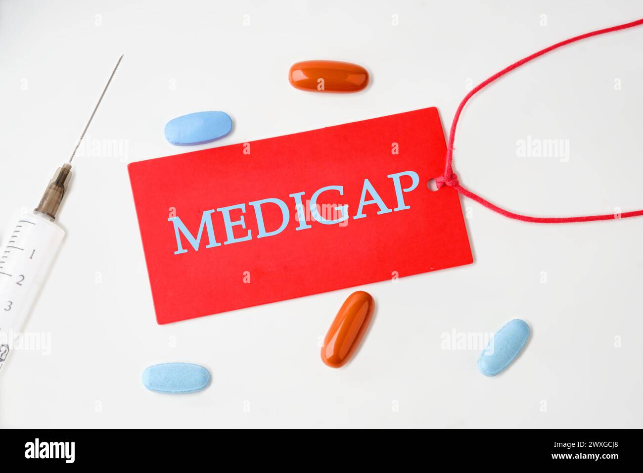 Concetto medico. MEDIGAP su un cartoncino rosso con una corda su sfondo bianco Foto Stock