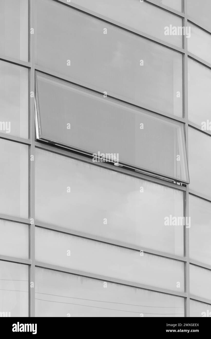 Edificio per uffici con facciata in vetro grigio chiaro, architettura dall'aspetto moderno che riflette le nuvolose finestre aperte del cielo. Foto Stock