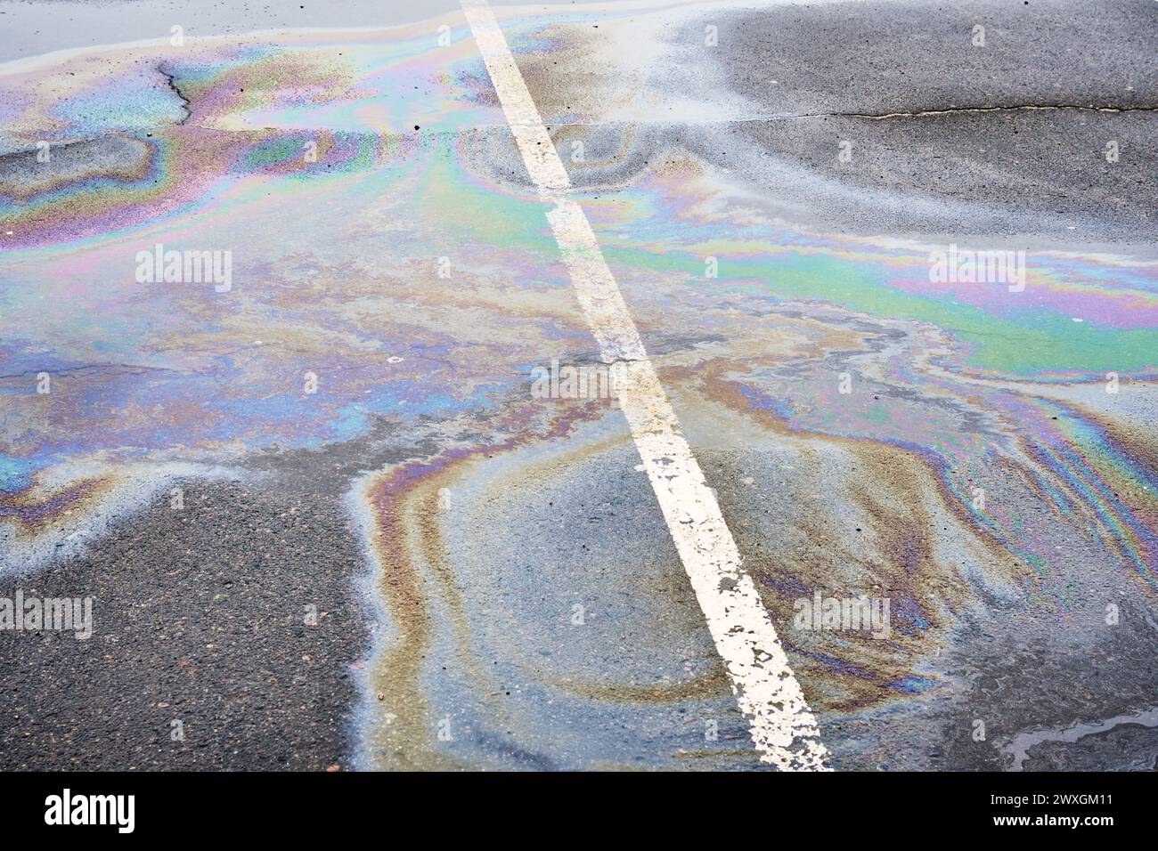 Fuoriuscita di olio su asfalto bagnato, parcheggio con linea di demarcazione. Problemi ambientali dell'inquinamento idrico Foto Stock