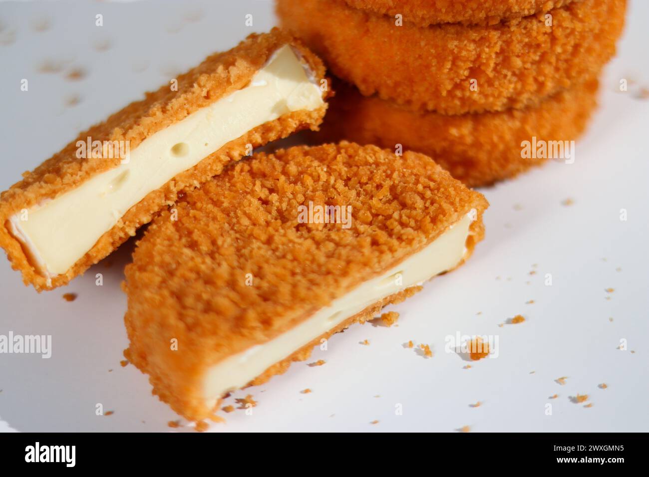 Una pila di camembert fritto con un taglierino di formaggio su sfondo bianco Foto Stock