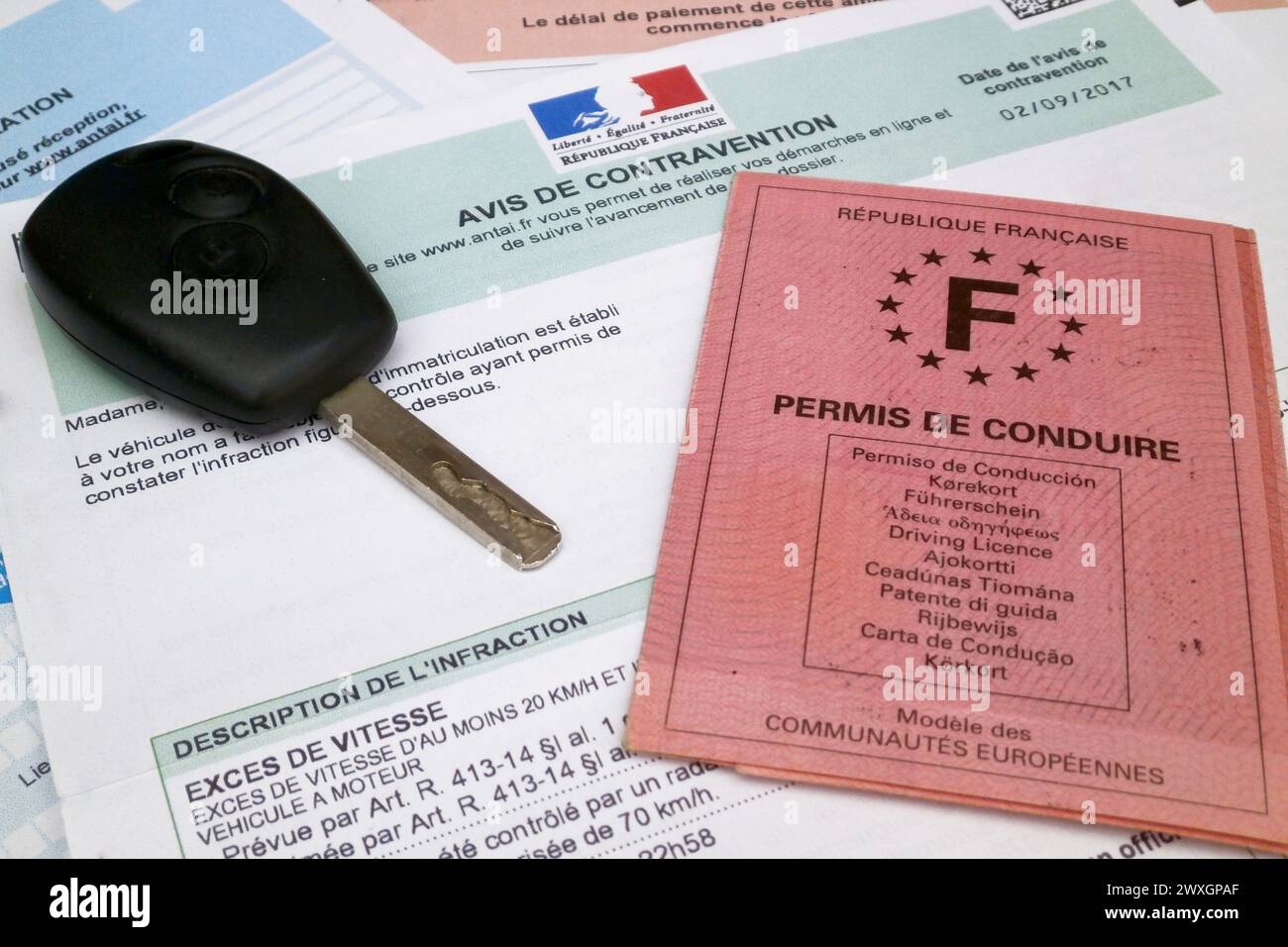 La patente di guida francese e una chiave di auto in cima a un biglietto francese per l'eccesso di velocità con i dettagli dell'infrazione e la data. Tutte le identificazioni lo hanno fatto Foto Stock