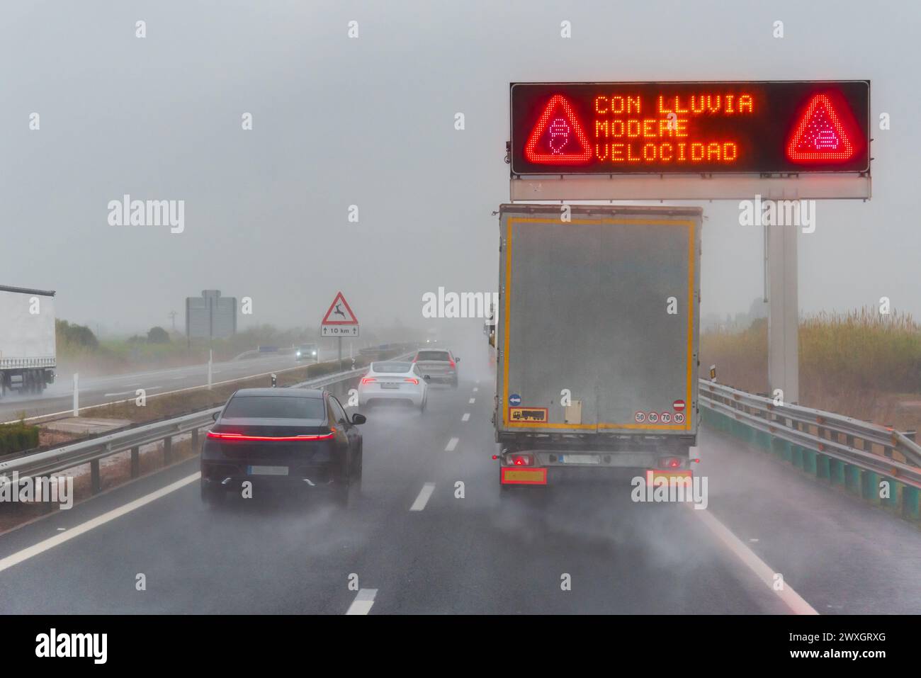 Pannello illuminato su un'autostrada con la leggenda sotto la pioggia, velocità moderata, in una giornata di pioggia. Foto Stock