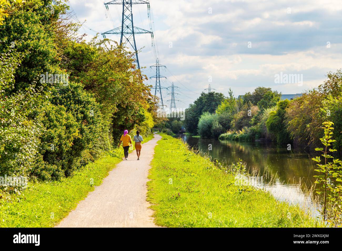 Due donne che camminano sul sentiero lungo il canale di navigazione River Lee vicino a Brimsdown, Londra, Regno Unito Foto Stock