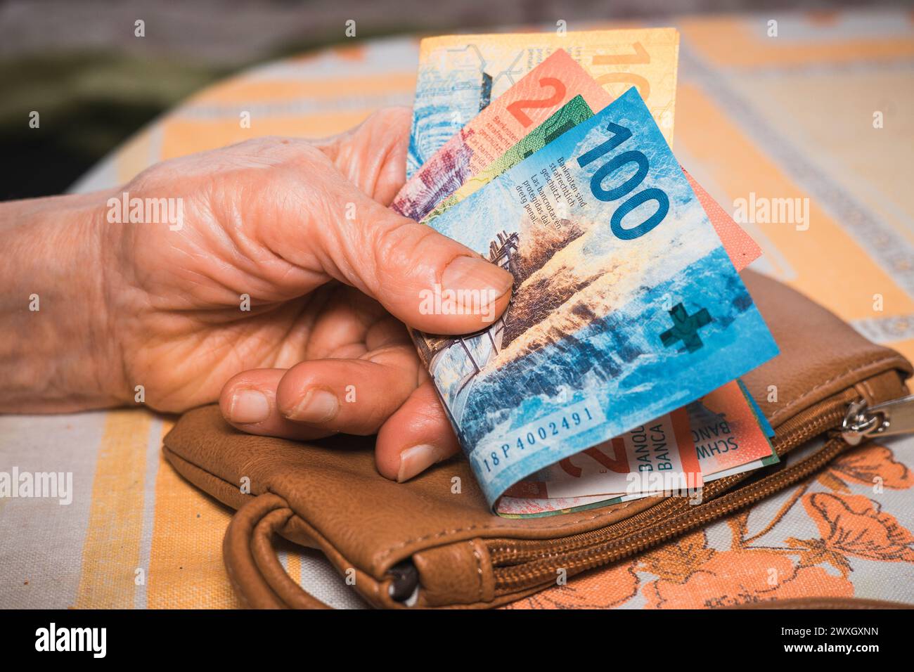 Una piccola quantità di franchi svizzeri nelle mani di un pensionato, concetto finanziario, problemi degli anziani in Svizzera Foto Stock
