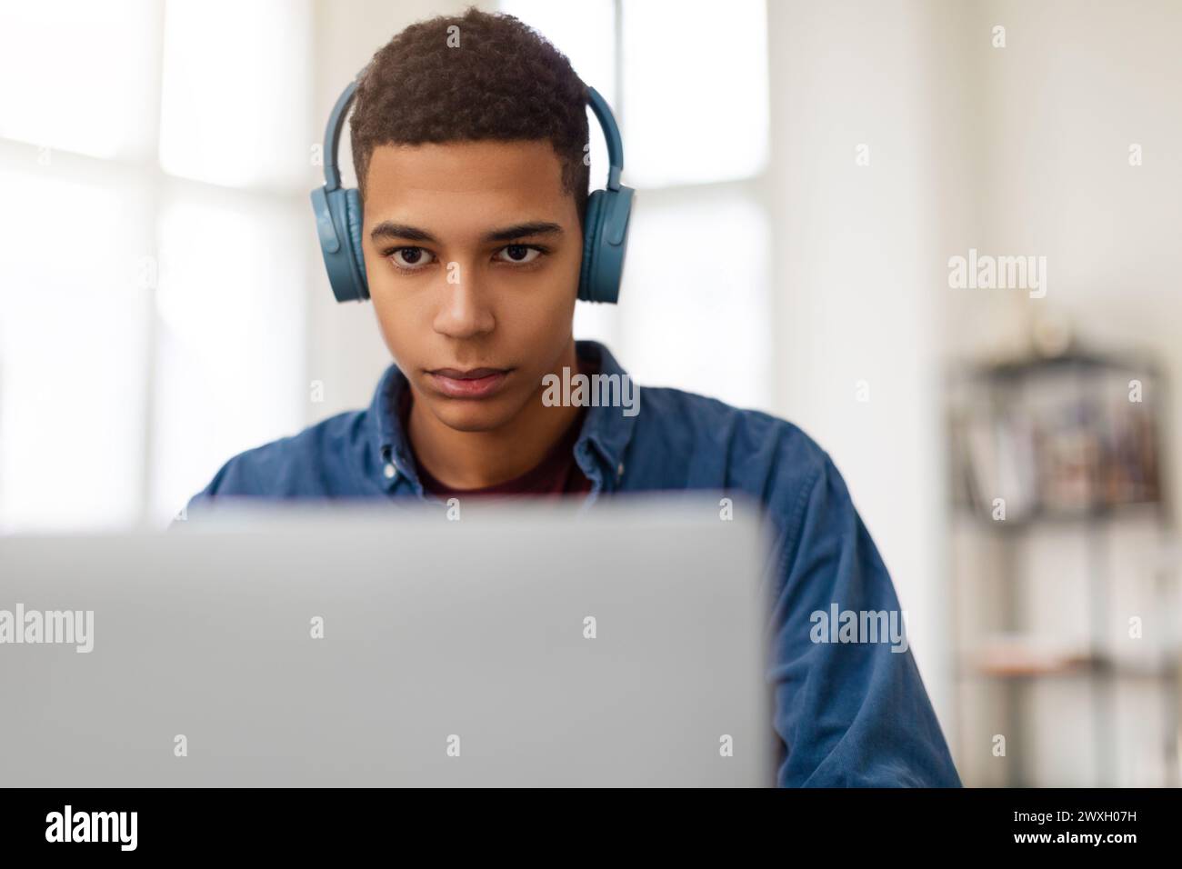 Giovane uomo con le cuffie che usa un computer portatile Foto Stock