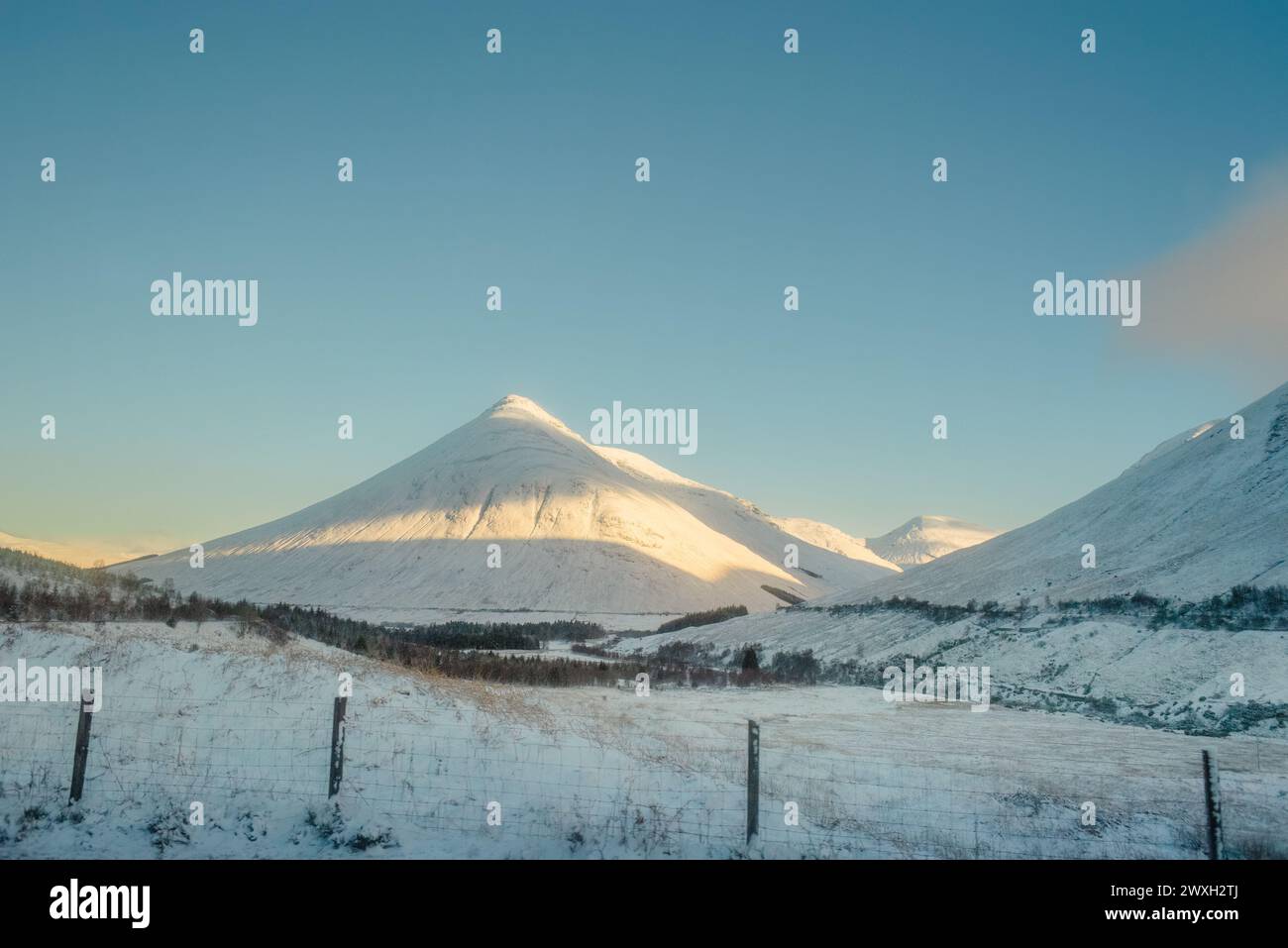 Beinn Dorain, una montagna conica, coperta di neve sotto un cielo blu, lungo la West Highland Way in Scozia Foto Stock