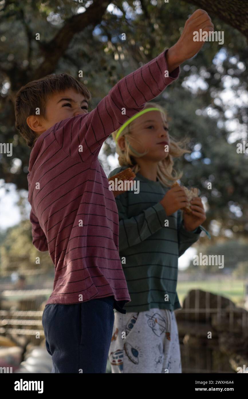 Due bambini mangiano un panino in natura e giocano Foto Stock