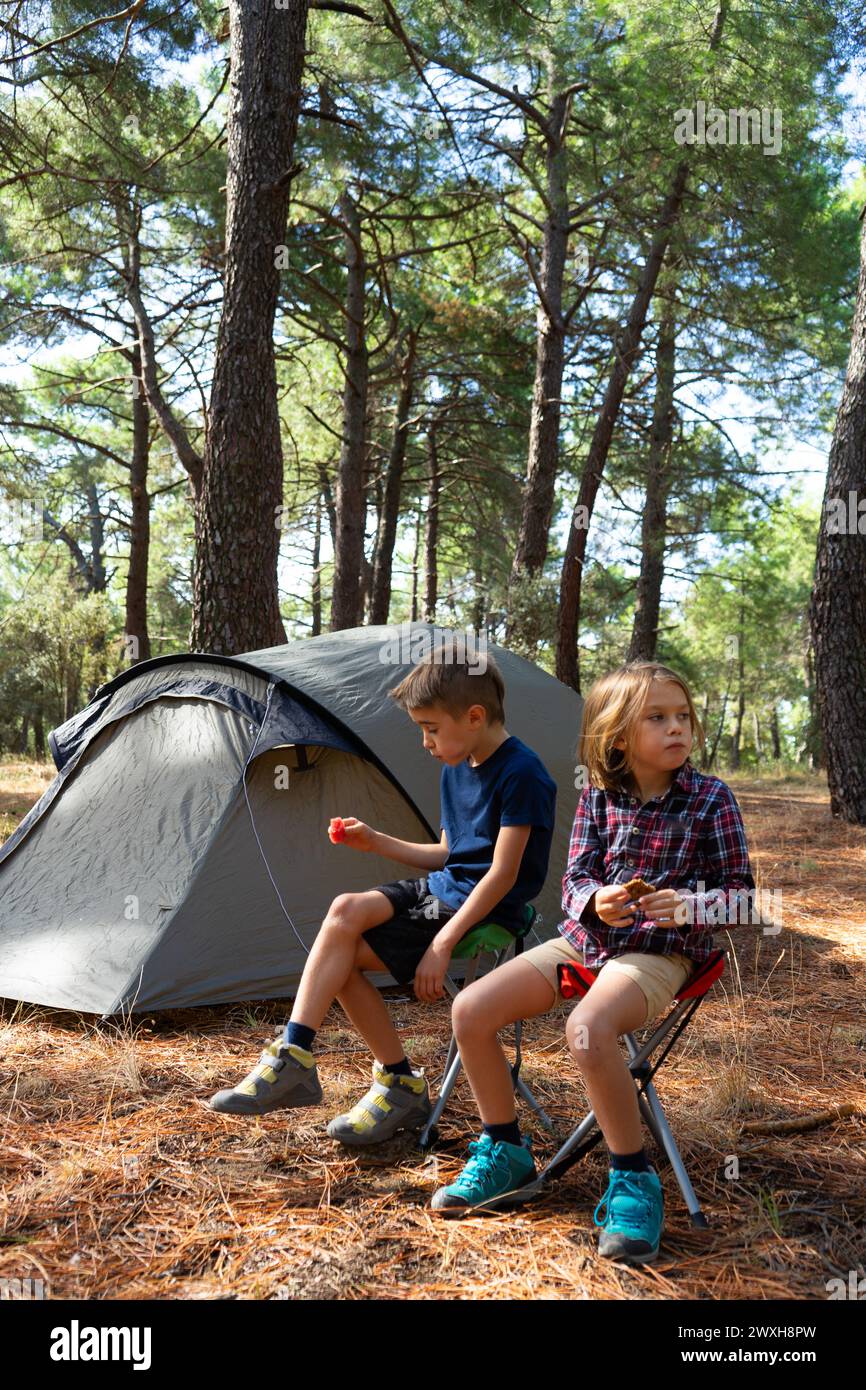 Due bambini mangiano nel bosco accanto alla loro tenda Foto Stock