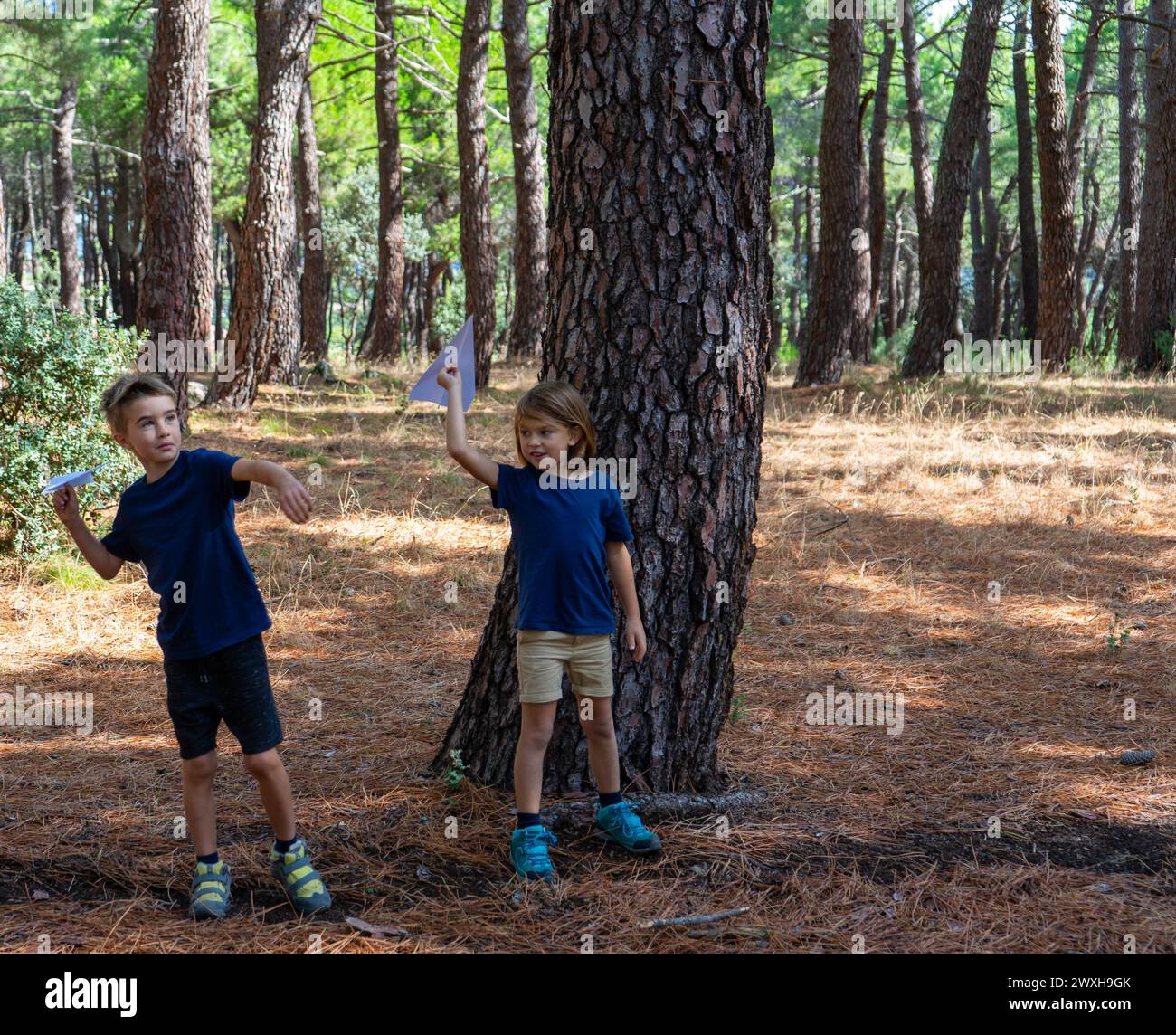 Due bambini che giocano con gli aeroplani di carta in natura Foto Stock
